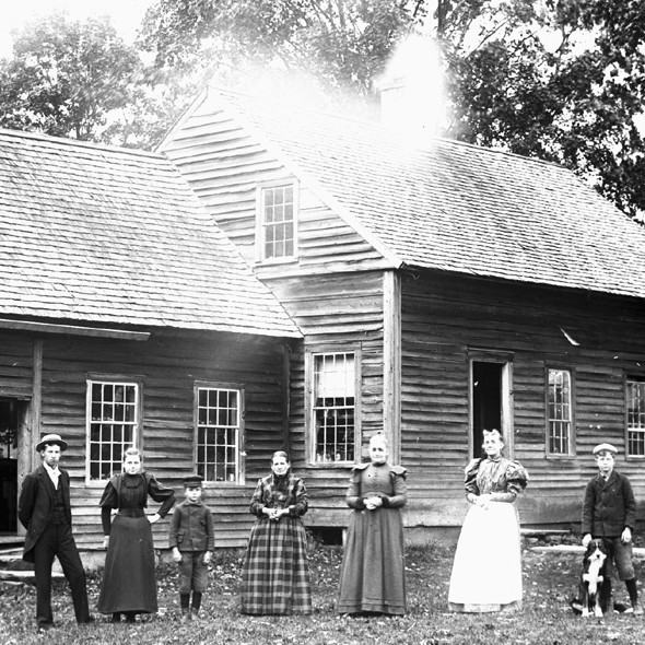 group of adults and children standing in front of a house