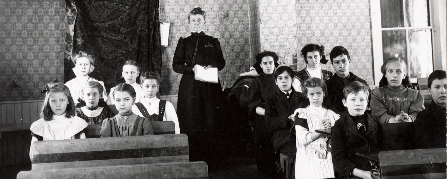 classroom with teacher standing and children sitting at desks