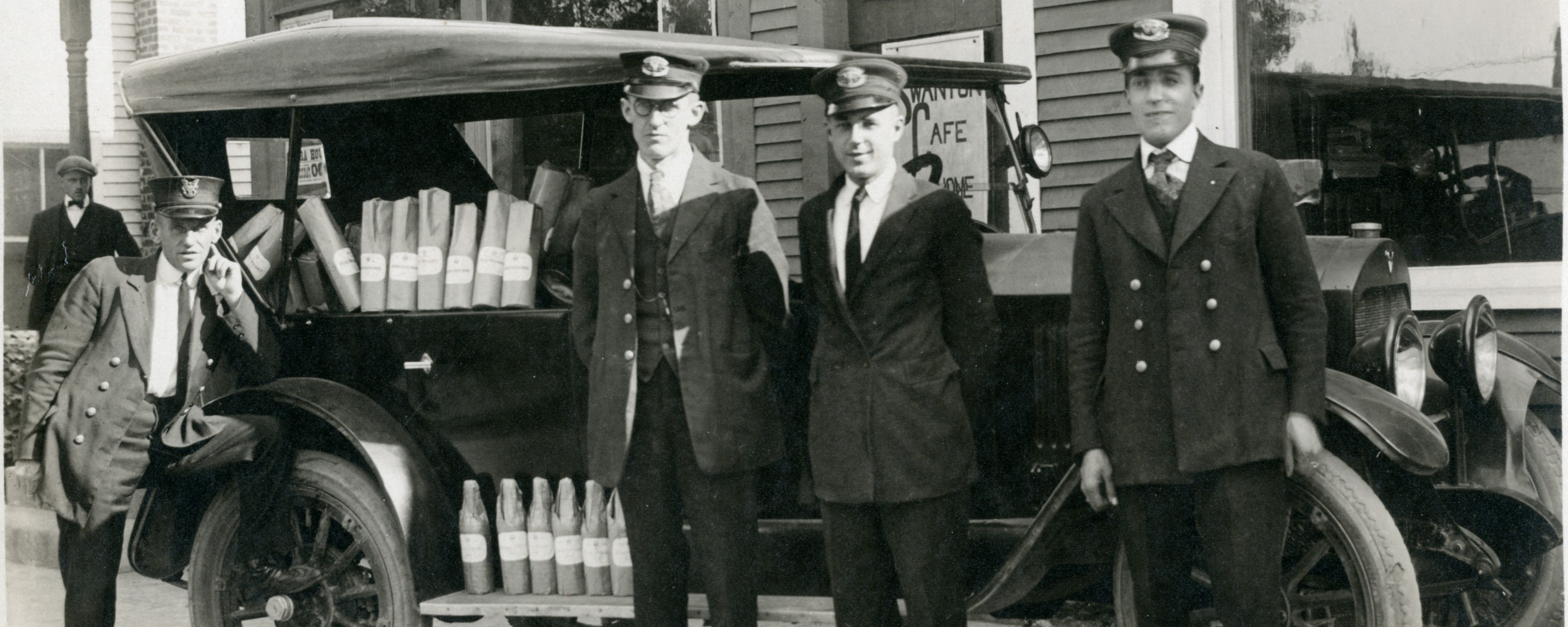 4 policemen standing by car alongside bootleg liquor