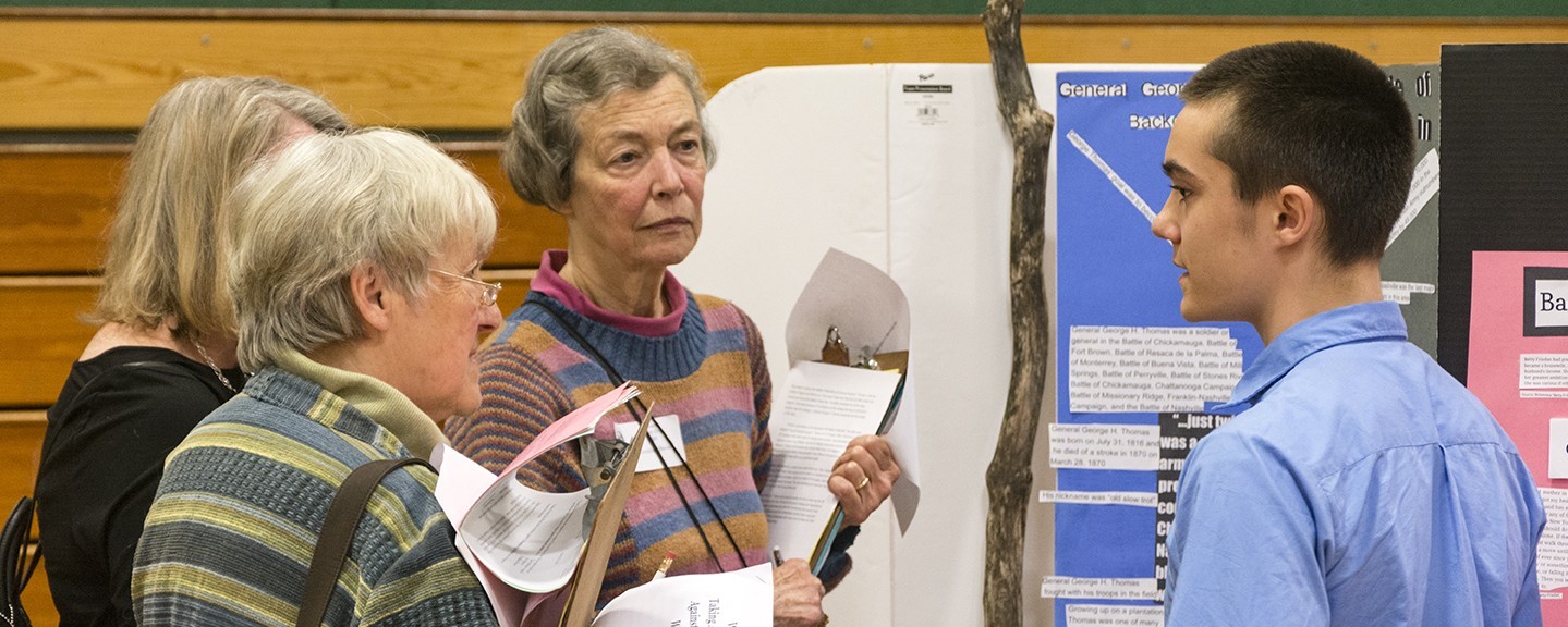 three women talking with a student about an exhibit